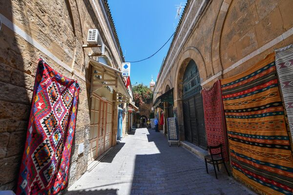 فرش‌های سنتی در 21 می 2022 روی دیوارهای اطراف یک مغازه در جاده های باریک مدینه قدیمی تونس به نمایش گذاشته شده است. - اسپوتنیک افغانستان  