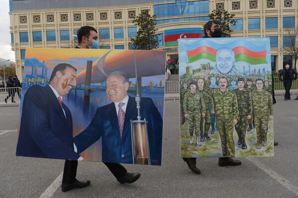 مردان در یکی از خیابان های شهر باکو نقاشی الهام علی اف رئیس جمهور آذربایجان به نمایش گذاشتن. - اسپوتنیک افغانستان  