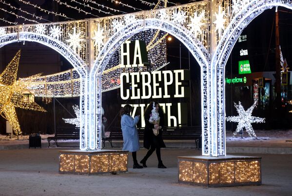 مردم در نزدیکی تأسیسات سال نو در میدان مرکزی پنج گوشه در مورمانسک قدم می زنند. - اسپوتنیک افغانستان  