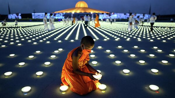 Буддийский монах устанавливает светодиодный светильник в рамках празднования Дня Земли, Таиланд  - اسپوتنیک افغانستان  