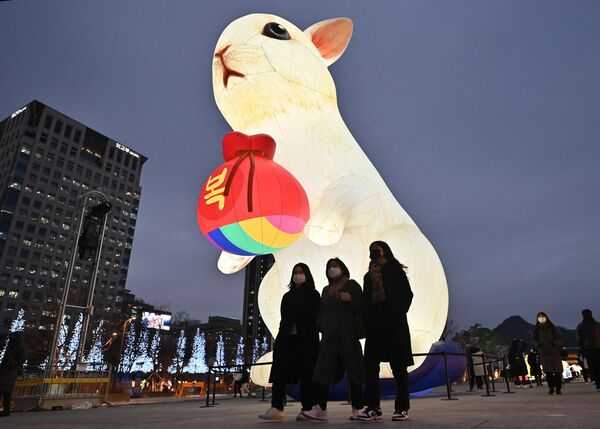 مردم در جشنواره فانوس سئول در میدان گوانگوامون در ۱۹ دسامبر ۲۰۲۲ از کنار یک فانوس نورانی خرگوش برای سال آینده می گذرند. - اسپوتنیک افغانستان  