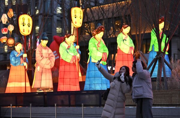 زوجی در جشنواره فانوس سئول در میدان گوانگوامون در سئول در 19 دسامبر 2022 در برابر فانوس های نورانی عکس سلفی می گیرند. - اسپوتنیک افغانستان  