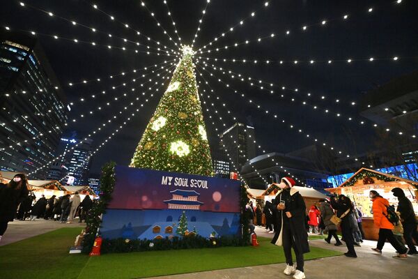 مردم در جشنواره فانوس سئول در میدان گوانگوامون در سئول در 19 دسامبر 2022 از کنار یک چراغ جشن کریسمس می گذرند. - اسپوتنیک افغانستان  