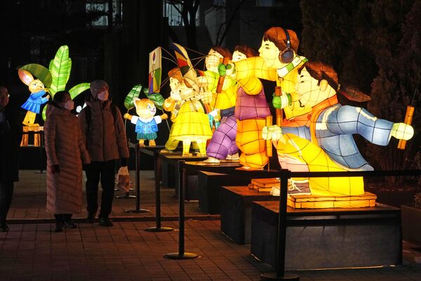 زن و شوهری در طول جشنواره فانوس در میدان گوانگوامون در سئول، کوریای جنوبی، دوشنبه، 19 دسامبر 2022 از کنار فانوس ها عبور می کنند. این جشنواره از 19 دسامبر تا 31 دسامبر ادامه خواهد داشت. (عکس از یونگ یوین یی خبرگزاری فرانسه) - اسپوتنیک افغانستان  