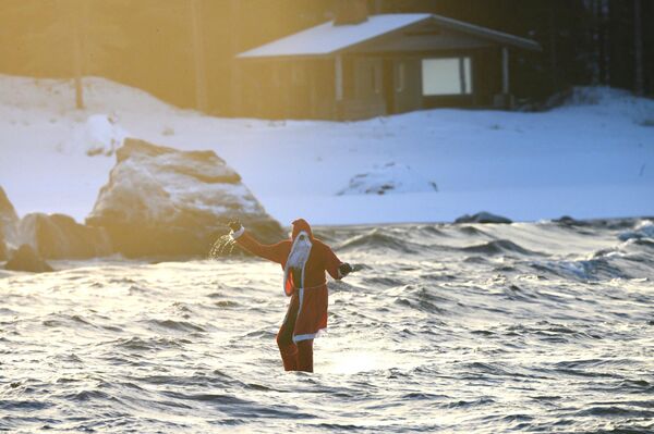 مردی را با لباس بابانوئل در حال سوار شدن بر روی تخته موج سواری در نزدیکی Nykarleby در غرب فنلاند. - اسپوتنیک افغانستان  