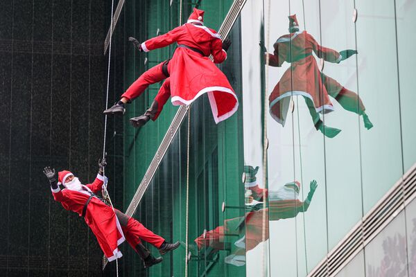 کوهنوردان با لباس بابا نوئل از ساختمان کلینیک کودکان مرکز پزشکی دانشگاه لیوبلیانا در لیوبلیانا، کشور اسلوونیا بالا می روند. - اسپوتنیک افغانستان  