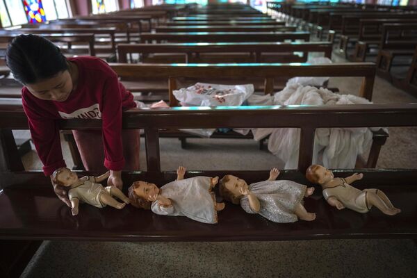 یک مراقب عروسک‌هایی را که به نمایندگی از عیسی شیرخوار نشان می‌دهند روی نیمکتی قرار می‌دهد تا برای کریسمس در گواهاتی هند آماده شود. جمعه، 23 دسامبر 2022(عکس از/Anupam Nath) - اسپوتنیک افغانستان  