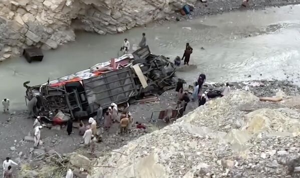 این نگاره که از یک ویدیو گرفته شده نشان می‌دهد که نیروهای امدادی در حال جستجوی بازماندگان در لاشه بس مسافربری که از جاده کوهستانی سر خورد و به دره عمیقی در دانا سر، ولایت خیبر پختونخوا، در جنوب غربی پاکستان افتاد، یکشنبه، 3 جولای 2022. یک مقام مسئول گفت: بس مسافربری از یک جاده کوهستانی سر خورد و در اثر باران شدید به عمق 200 فوت (61 متر) در دره سقوط کرد که منجر به کشته شدن حداقل 18 نفر و زخمی شدن 12 نفر دیگر شد. (عکس خبرگزاری فرانسه) - اسپوتنیک افغانستان  
