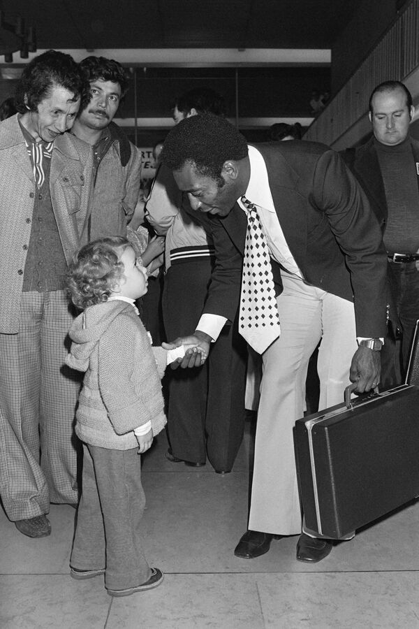 پلی بازیکن فوتبال برازیلی در 12 سپتامبر 1976، هنگام ورود به میدان هوایی اورلی، همراه با تیم نیویارک کاسموس خود برای شرکت در یک مسابقه دوستانه مقابل پاری سن جرمن، در 15 سپتامبر 1976، با یک کودک روبرو میشود. - اسپوتنیک افغانستان  