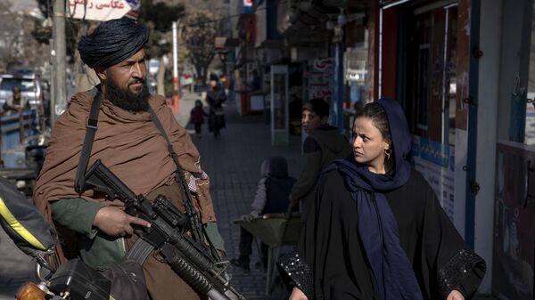 Женщина смотрит на бойца движения Талибан на улице в Кабуле, Афганистан - اسپوتنیک افغانستان  