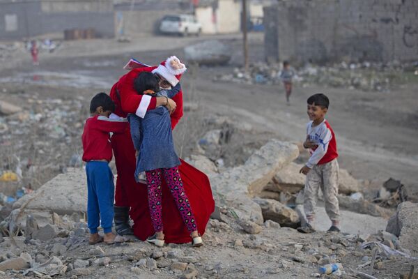محمد معروف هدایایی را در حالی که لباس سنت نیکلاس (بابانوئل) به تن دارد بین کودکان ساکن در یک محله فقیر نشین در نزدیکی مرکز شهر جنوبی بصره در عراق توزیع می کند.26 دسامبر 2022 - اسپوتنیک افغانستان  