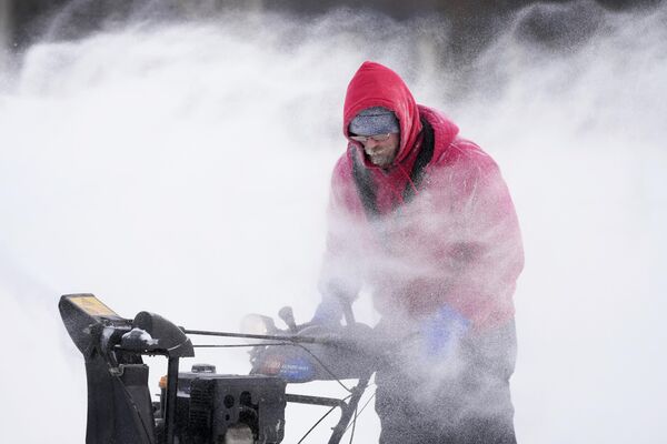 مارک سورتر جمعه، 23 دسامبر 2022، در دموین، آیووا، برف را از یک پیست اسکیت روی یخ در مرکز شهر پاک می‌کند. - اسپوتنیک افغانستان  