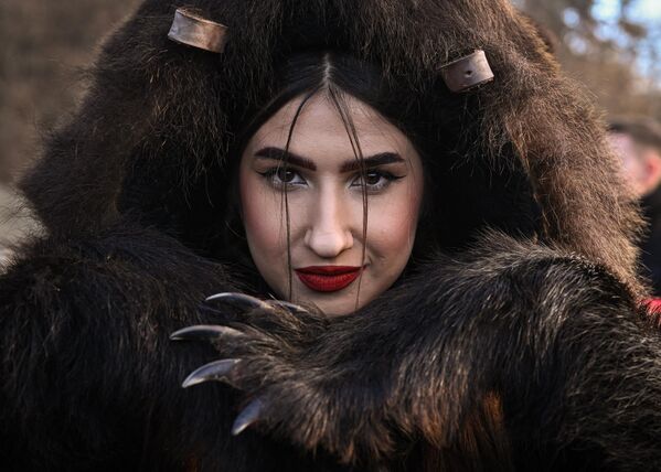 یک دختر با لباس پوست خرس در رژه پوست خرس در کومانستی، رومانیا، در 30 دسامبر 2022 ژست می گیرد. - بیش از 200 خرس و ده ها نوازنده، در محاصره پولیس و گردشگران، در پایان مراسم شرکت کردند. رژه سال مردان و زنان جوان با پوشیدن پوست خرس واقعی و لباس های سنتی رژه رفتند تا ارواح خبیث سال آینده را بدرقه کنند. - اسپوتنیک افغانستان  