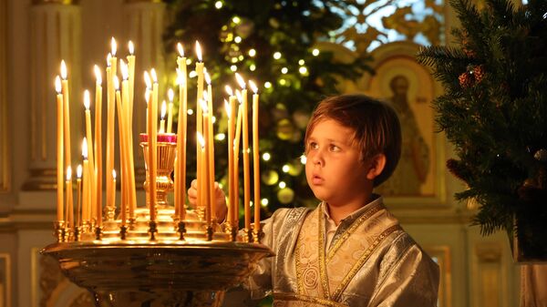 Мальчик зажигает свечу во время празднования православного Рождества в Русской православной церкви в Шардже - اسپوتنیک افغانستان  