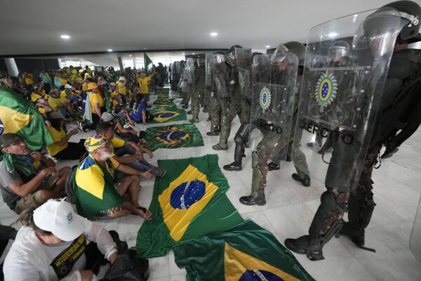معترضان، حامیان رئیس جمهور سابق برزیل، ژایر بولسونارو، پس از هجوم به کاخ پلانالتو، در برازیلیا، مقابل پولیس نشسته اند. - اسپوتنیک افغانستان  