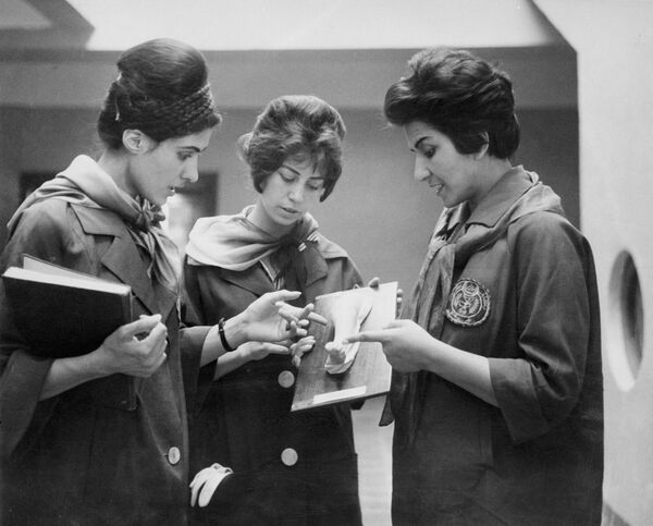 تصویری که در سال 1962 در دانشکده طب در کابل از دو دانشجوی طب افغانستان (چپ و مرکز) گرفته شده است که در حال گوش دادن به سخنان استاد خود در حالی که مشغول بررسی یک مدل هستند که بخشی از بدن انسان را نشان می دهد. (عکس از STAFF / AFP) - اسپوتنیک افغانستان  