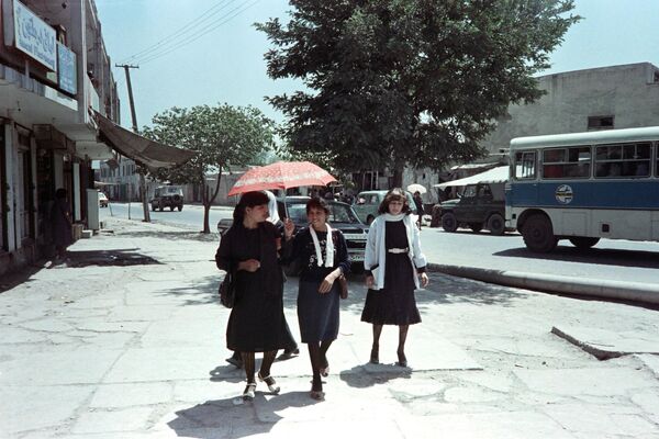 دختران با لباس غربی در 16 اگوست 1988 در جریان جنگ شوروی و افغانستان در خیابانی در کابل قدم می زنند. (عکس از سعید خان / خبرگزاری فرانسه) - اسپوتنیک افغانستان  