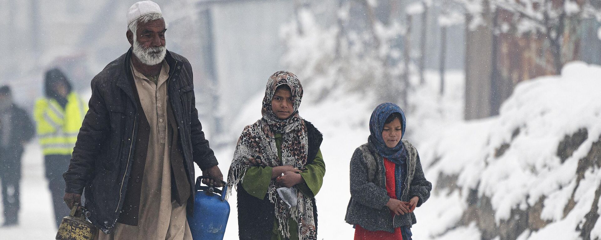 Мужчина с газовыми баллонами идет рядом с детьми по улице во время снегопада в Кабуле, Афганистан - اسپوتنیک افغانستان  , 1920, 14.01.2023