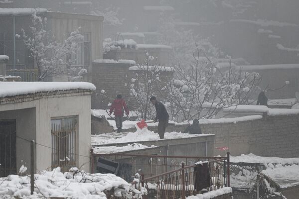 ساکنان برف را از پشت بام خانه خود در هنگام بارش برف در کابل در 21 جدی 1401 پارو می کنند. (عکس از وکیل کوهسار / خبرگزاری فرانسه) - اسپوتنیک افغانستان  