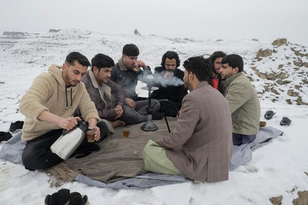 مردان افغان در 8 جنوری 2023 در میان برف در کنار دریاچه قرغه در کابل نشسته اند، چای می نوشند. (عکس از وکیل کوهسار / خبرگزاری فرانسه) - اسپوتنیک افغانستان  