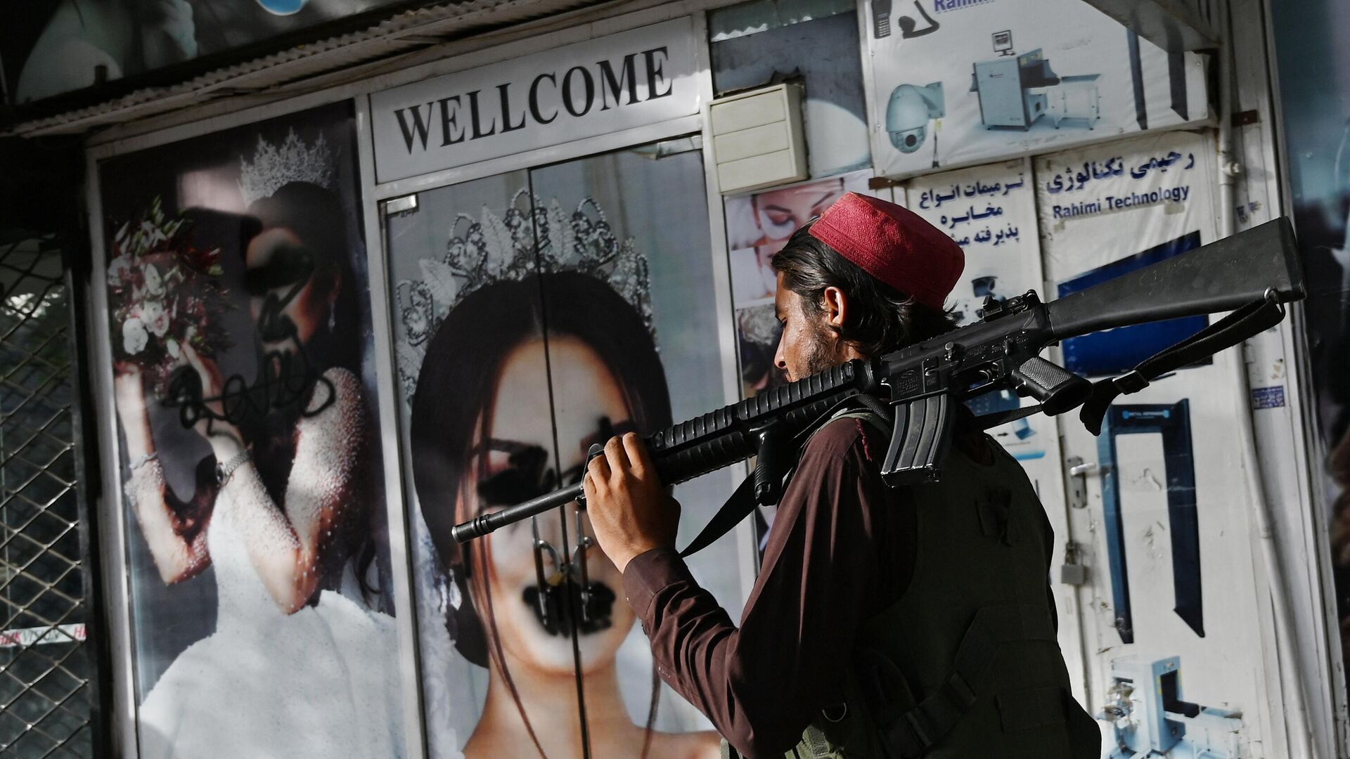 Боец движения Талибан проходит мимо кабульского салона красоты с изображениями женщин, лица которых закрашены аэрозольной краской, 2021 год - اسپوتنیک افغانستان  , 1920, 21.01.2023