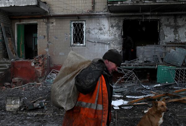مردي که زباله ها را از داخل خانه اي که در اثر تيراندازي شبانه در گورلوفکا آسیب دیده است خارج مي کند. - اسپوتنیک افغانستان  
