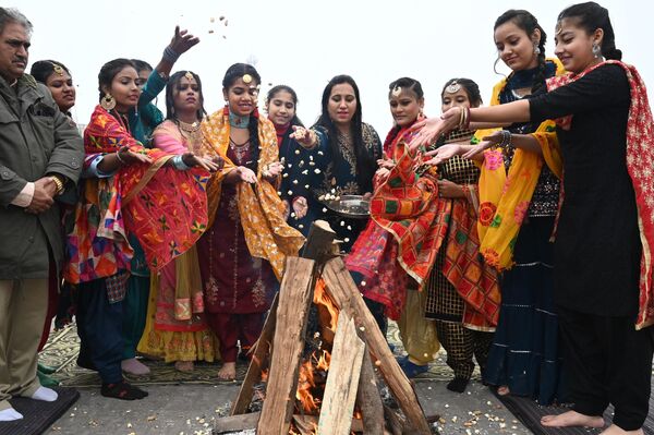 دانشجویان در طول جشن جشنواره لوهری در امریتسار در 12 جنوری 2023, جورای, بادام زمینی و شیرینی در آتش می اندازند.(عکس از ناریندر نانو / خبرگزاری فرانسه) - اسپوتنیک افغانستان  