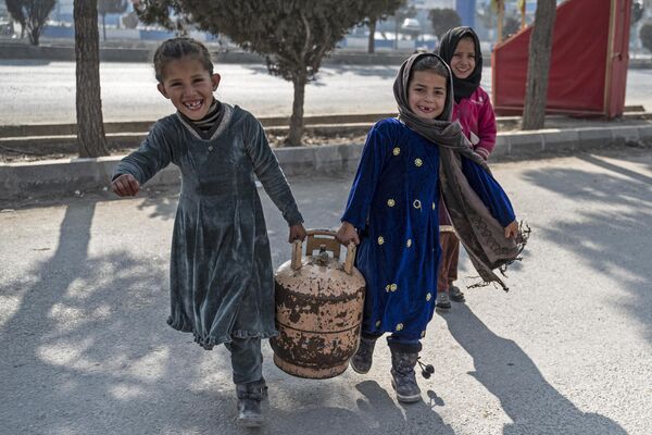 دختران افغان در 17 جنوری 2023 یک بالن گاز را در خیابانی در کابل حمل می کنند. (عکس از وکیل کوهسار / خبرگزاری فرانسه) - اسپوتنیک افغانستان  