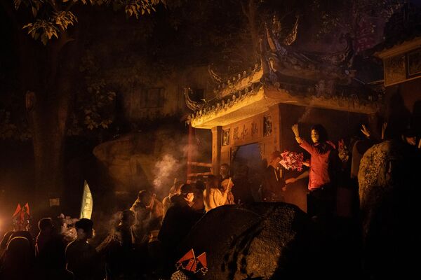 مردم هنگام قدم زدن در اطراف معبد A-Ma هنگام شروع جشن های سال نو قمری چینی در ماکائو در 21 جنوری 2023، چوب های بخار به دست می گیرند. - اسپوتنیک افغانستان  