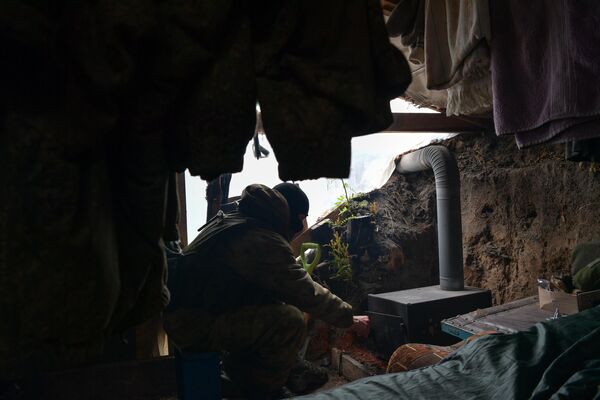 یکی از اعضای کندک قطب شمال در محل زندگی سربازان در حال روشن کردن بخاری در بخش جنوبی عملیات ویژه نظامی. - اسپوتنیک افغانستان  