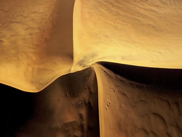 سسریم، صحرای نامیب، نامیبیا: منحنی های صحرای نامیب. این مجموعه عکس در نامیبیا در صحرای نامیب با استفاده از یک هلیکوپتر ساخته شده است.    در طول پرواز سعی کردم اشکال غیرعادی ایجاد شده توسط خورشید، نور و سایه را همراه با تپه های شنی به تصویر بکشم.    عکسی از یاروسلاو هورا، عکاس چک، برنده رده بیابان‌ها تا جنگل‌های بارانی (پورتفولیو) بهترین عکاس سفر سال 2022. - اسپوتنیک افغانستان  