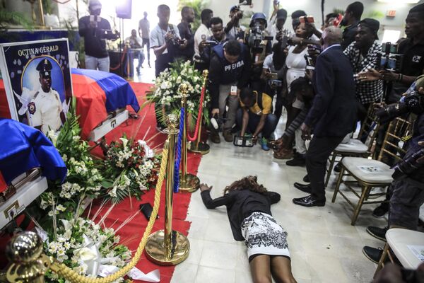 زنی روی زمین در کنار تابوت‌ها گریه می‌کند و اجساد سه افسر پلیس را در دست دارد که در حین انجام وظیفه در آکادمی پلیس در پورتو پرنس، هائیتی، سه‌شنبه، 31 جنوری 2023 کشته شدند.این افسران در روز 30 جدی ماه در کمین اعضای باند در پایتخت کشته شدند.(AP Photo/Odelyn Joseph) - اسپوتنیک افغانستان  