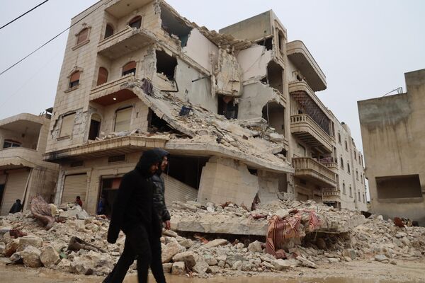 دو مرد پس از زلزله در شهر سرمده در حومه استان ادلب در شمال غربی سوریه از کنار ساختمانی به شدت آسیب دیده عبور می کنند.(عکس از محمد الرفاعی / خبرگزاری فرانسه) - اسپوتنیک افغانستان  