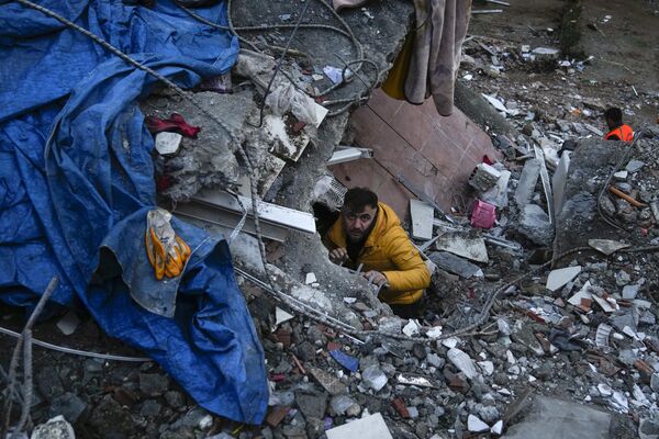 مردی در حال جستجوی افراد در ساختمان ویران شده در آدانا، ترکیه، دوشنبه، 6 فبروری 2023 است. - اسپوتنیک افغانستان  