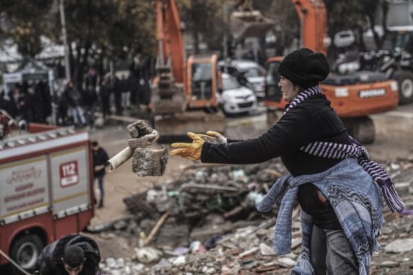 زنی در حالی که با تیم های اضطراری در غازی اینتاپ ترکیه به دنبال افراد می گردد، آوارهای ساختمان ویران شده را برمی دارد، دوشنبه، 6 فوریه 2023. - اسپوتنیک افغانستان  