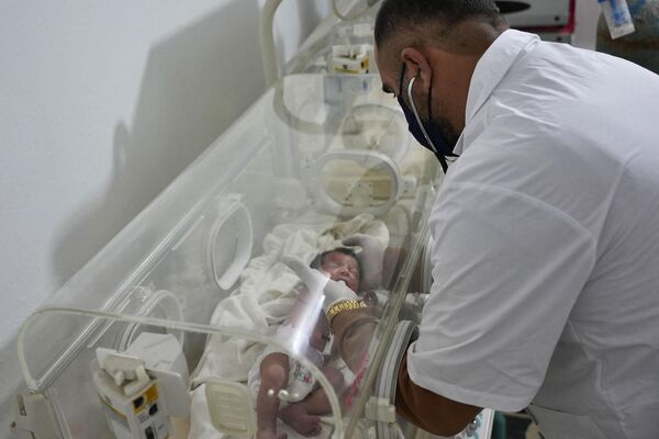 نوزاد تازه متولد شده ای که هنوز توسط بند نافش به مادرش بسته شده بود و زنده از زیر آوار خانه ای در شمال سوریه در پی زلزله مرگبار بیرون کشیده شده بود، تحت مراقبت های پزشکی توسط &quot;دکتر هانی معرفت&quot; در کلینیکی در شمال سوریه قرار گرفت. این تصویر در شهر عفرین، در 7 فبروری 2023 گرفته شده است.خلیل السوادی، پسر کاکای این نوزاد، گفت که این نوزاد تنها بازمانده خانواده نزدیکش است که بقیه آنها در اثر زلزله 7.8 ریشتری که سوریه و ترکیه همسایه را لرزاند و خانه خانواده را در شهر جیندایریس که تحت کنترل شورشیان بود، کشته شدند.(عکس از رامی السید / خبرگزاری فرانسه) - اسپوتنیک افغانستان  