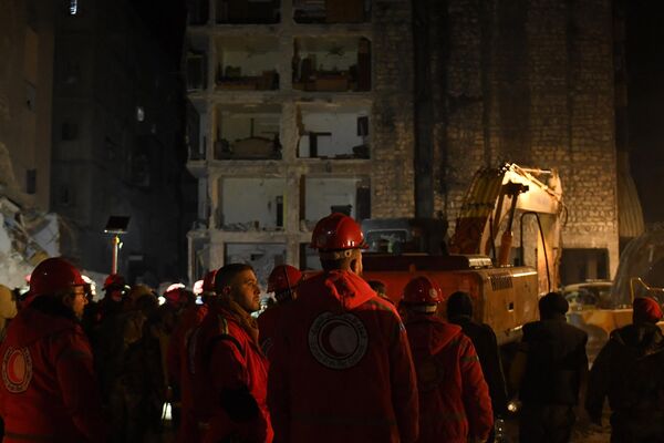 نجات دهندگان در 8 فبروری 2023، دو روز پس از زمین لرزه مرگبار سوریه و ترکیه، در میان ویرانه های ساختمان فروریخته در شهر حلب در شمال سوریه جستجو می کنند. - اسپوتنیک افغانستان  