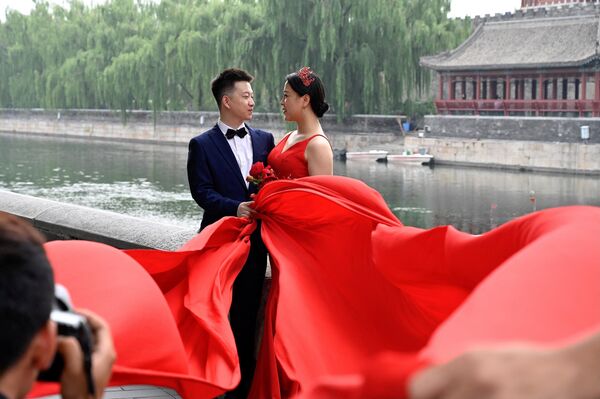 یک زن و شوهر در طول جشنواره &quot;کیکسی&quot; که به عنوان روز ولنتاین چینی نیز شناخته می شود در پکن عکس یادگاری می گیرند.این عکس در 14 آگوست 2021 گرفته شده است.(عکس از جید گا / خبرگزاری فرانسه) - اسپوتنیک افغانستان  