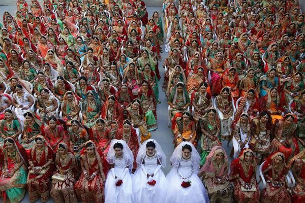 عروس های هندی برای یک عکس دسته جمعی در طول یک عروسی دسته جمعی در سورات، هند، دور هم می نشینند.دوصد و شصت و یک زوج جوان، از جمله شش زوج مسلمان و سه زوج مسیحی، در مراسم عروسی دسته جمعی به میزبانی تاجر هندی ماهش ساوانی، که چندین سال است بودجه عروسی دختران بی پدر در شهر سورات را تامین می کند، ازدواج کردند.عروسی در هند بسیار گران قیمت تمام می شود که خانواده عروس معمولاً به داماد جهیزیه زیادی از پول نقد و هدایا پرداخت می کنند.این عکس یکشنبه، 23 دسامبر 2018، گرفته شده است.(عکس/عکس اجیت سولانکی) - اسپوتنیک افغانستان  