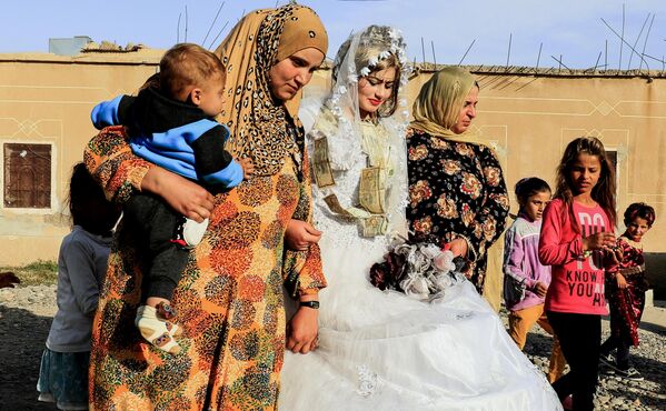 زنان سوری، عروس هبه (در مرکز) را در اولین جشن عروسی پس از بیرون راندن گروه دولت اسلامی عراق شام (داعش) از شهر شرقی رقه، در حومه غربی جزره، همراهی می کنند.این عکس در 27 اکتبر 2017، گرفته شده است. - اسپوتنیک افغانستان  