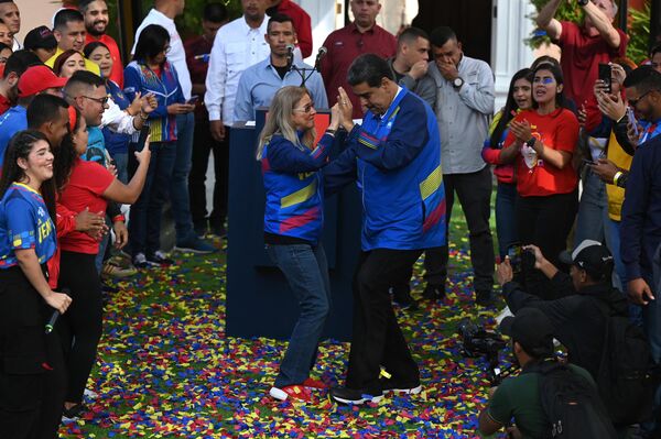 رئیس جمهور ونزوئلا نیکلاس مادورو (سمت راست تصویر) و بانوی اول سیلیا فلورس هنگام ورود برای شرکت در جلسه جشن روز جهانی جوانان در کاخ ریاست جمهوری میرافلورس در کاراکاس، در 12 فبروری 2023، می رقصند.(عکس از فدریکو پارا / خبرگزاری فرانسه) - اسپوتنیک افغانستان  