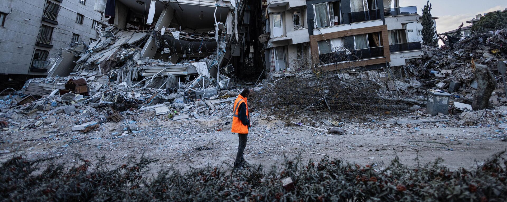 Спасатель проходит мимо частично разрушенных в результате землетрясений зданий в городе Антакья, Турция - اسپوتنیک افغانستان  , 1920, 25.02.2023