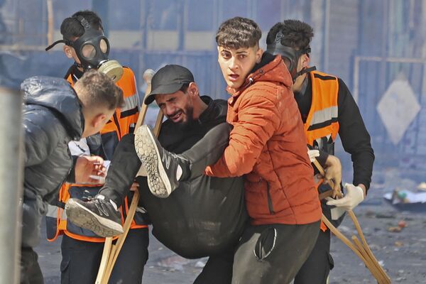 فلسطینی‌ها یک مرد مجروح را در جریان حمله اسرائیل به شهر نابلس کرانه باختری انتقال میدهند. - اسپوتنیک افغانستان  