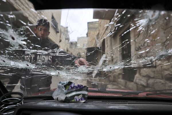 یک جوان فلسطینی به یک شیشه  پر از مرمی در خارج از خانه که در طی حمله  ارتش اسرائیل در شهر باستانی نابلس مورد حمله قرار گرفته است اشاره می کند. - اسپوتنیک افغانستان  