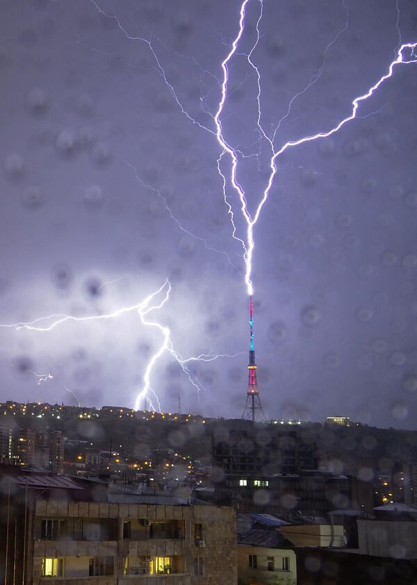 عکس از پنجره ای گرفته شده است که پر از قطرات باران است. رعد و برق در 4 اکتوبر 2020 به یک برج تلویزیونی در ایروان ارمنستان برخورد کرد. - اسپوتنیک افغانستان  