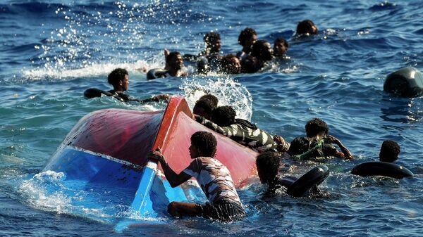 Мигранты рядом с перевернутой деревянной лодкой во время кораблекрушения у острова Лампедуза - اسپوتنیک افغانستان  