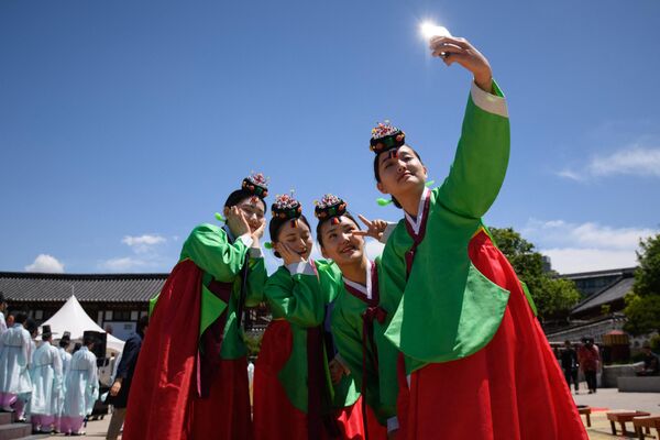 زنان جوانی که لباس سنتی هانبوک به تن دارند، برای عکس گرفتن به دنبال مراسم سنتی روز رسیدن به سن بلوغ در روستای نمسان هانوک در سئول. در این مراسم سن 19 سالگی راجشن می گیرند که در این سن دختران قادر به  رای دادن تا نوشیدن الکل است. - اسپوتنیک افغانستان  