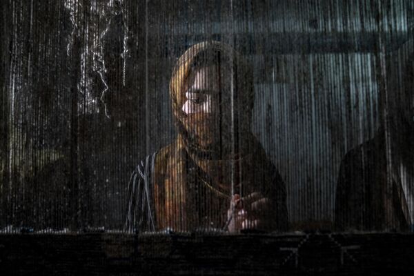 یک زن افغانستانی در یک کارخانه قالین سنتی در کابل، افغانستان، دوشنبه 6 مارچ 2023 قالین می بافد.پس از به قدرت رسیدن طالبان در افغانستان، زنان از بسیاری از حقوق اولیه خود محروم شده اند. - اسپوتنیک افغانستان  