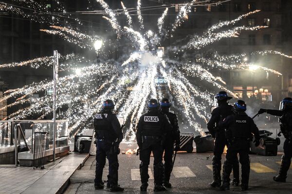 افسران پلیس در مقابل آتش بازی معترضان در جریان تظاهراتی ایستاده اند که پس از آن که دولت فرانسه اصلاحات حقوق بازنشستگی را بدون رأی گیری در پارلمان با استفاده از ماده 49.3 قانون اساسی در لیون به اجرا گذاشت. - اسپوتنیک افغانستان  