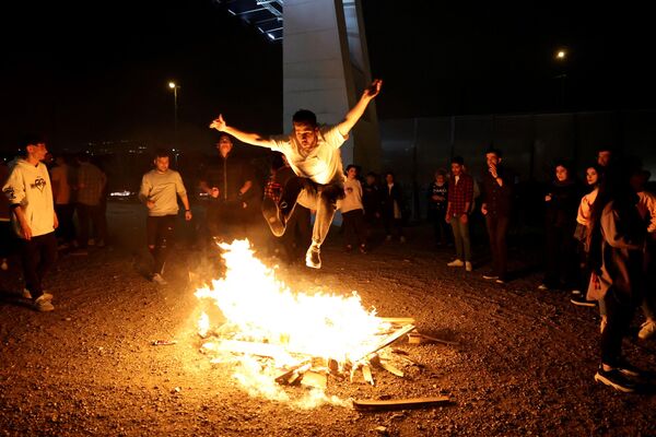 یک ایرانی در حال آتش بازی در مراسم چهارشنبه سوری.ایران چهارشنبه آخر سال را با آتش بازی جشن می گیرند. - اسپوتنیک افغانستان  